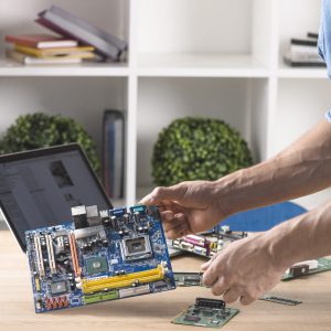 close-up-male-technician-holding-modern-computer-motherboard-from-table